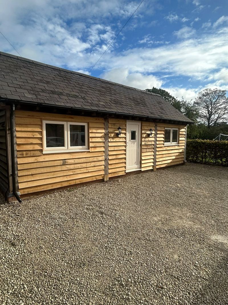 After: the carport enclosed in oak cladding with windows and a door