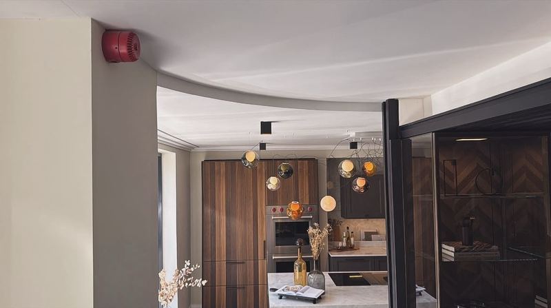 A finished kitchen showroom with a curved plasterboard ceiling bulkhead and glass pendant lights